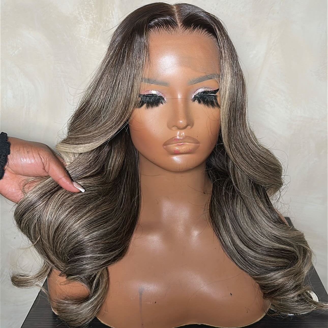 Mannequin head with a gray and black wig on a neutral background