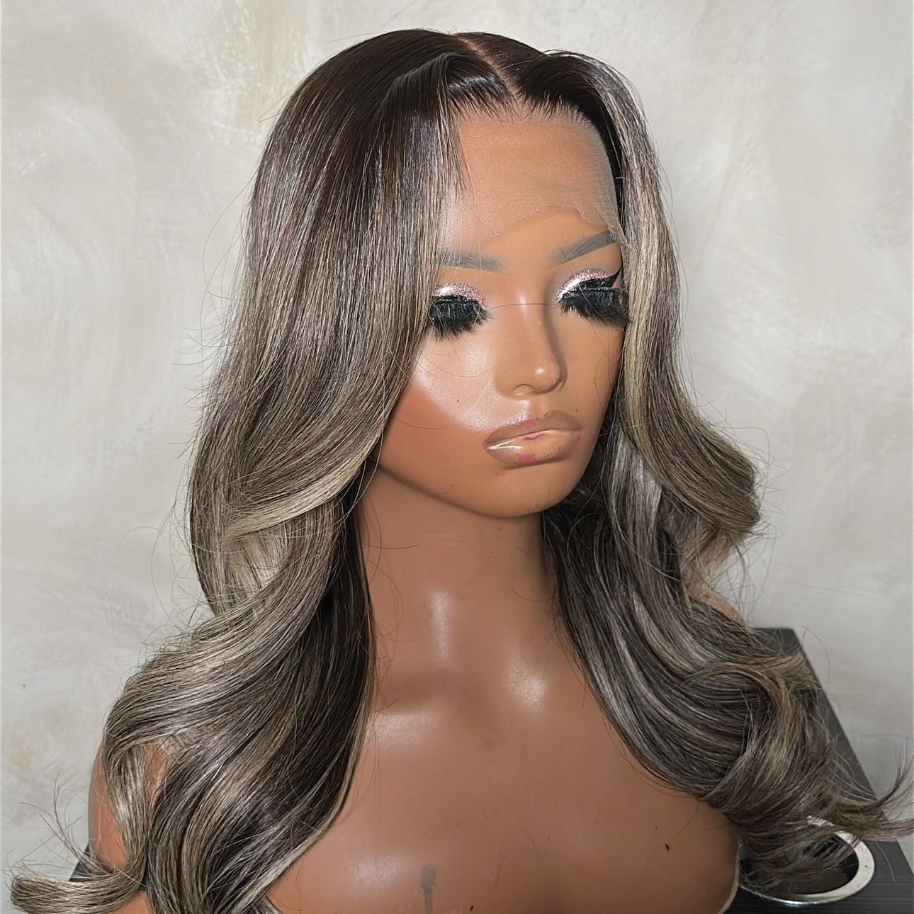 Mannequin head with a gray and black ombre wig on a neutral background