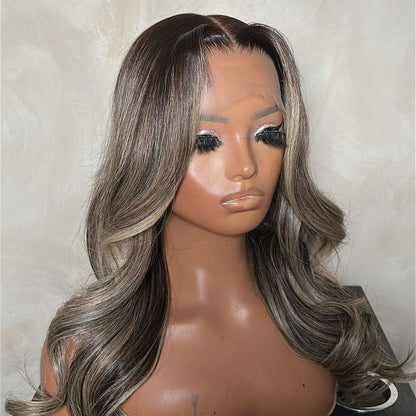 Mannequin head with a gray and black ombre wig on a neutral background