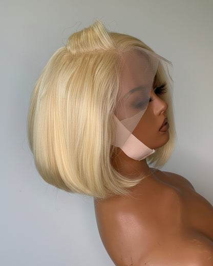 Blonde wig on a mannequin head against a plain background