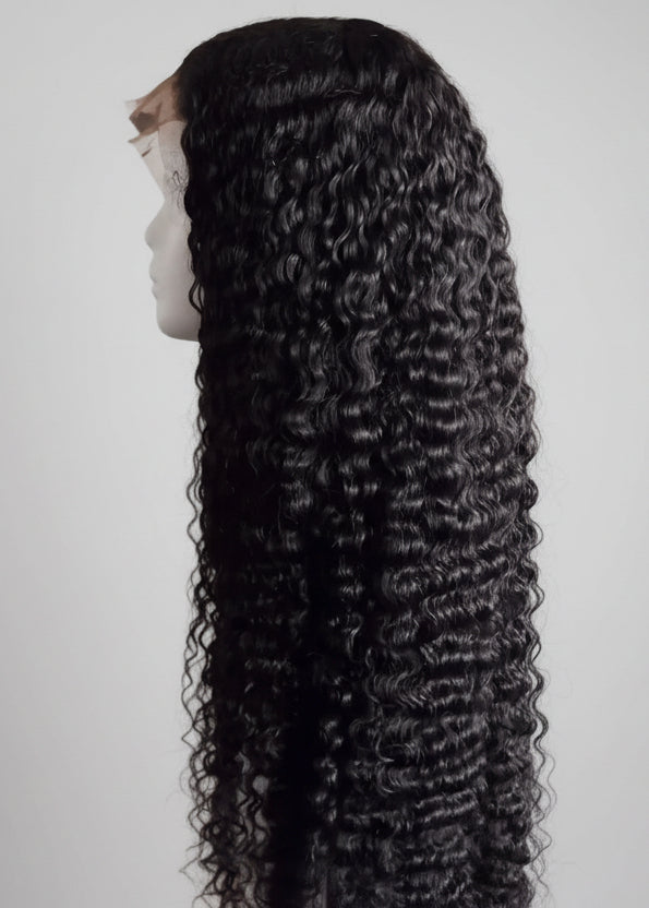 Black curly wig on a mannequin head against a white background - The Hair Source
