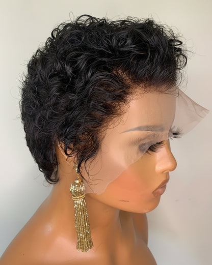 Mannequin head with a short, curly black wig and gold tassel earrings on a plain background