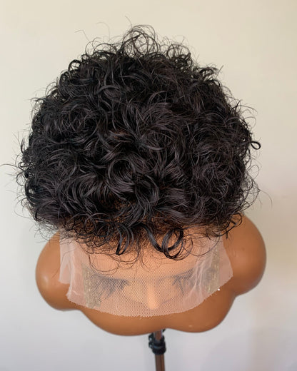 Black curly wig on a mannequin head against a white background